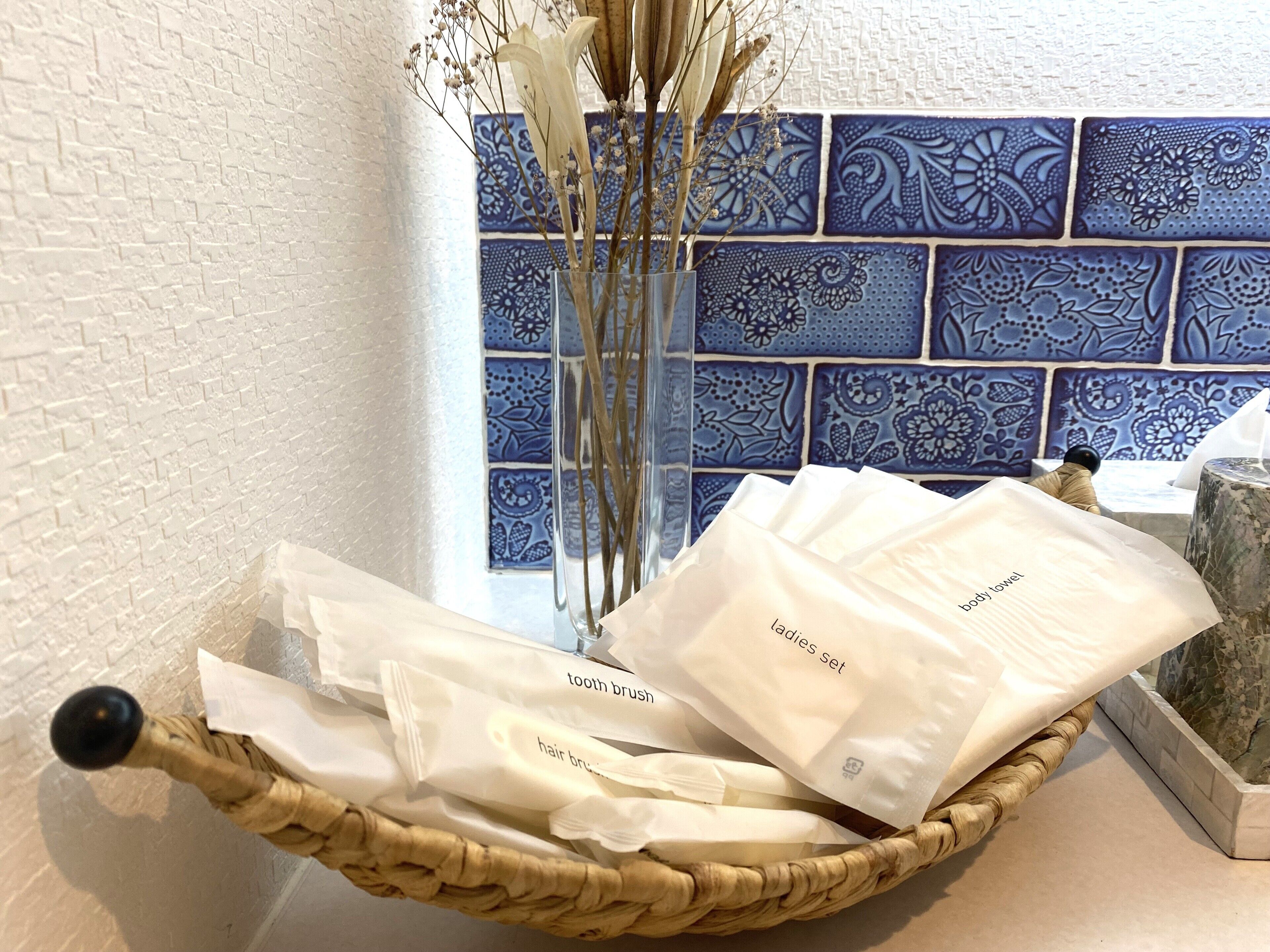 A wicker basket containing toiletries on a counter with a blue patterned tile backsplash.