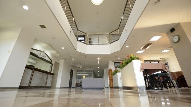 A spacious lobby with a high ceiling, a central staircase, and a reception desk. - Tsukuba View Hotel (Joso)
