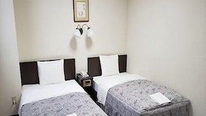 Une chambre d’hôtel avec deux lits, une table de chevet avec un téléphone, un tableau encadré au mur et une paire de chaussons sur le sol.