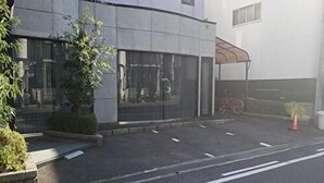 Un bâtiment moderne doté d’une entrée abritée, un vélo garé à l’intérieur et une route dégagée devant.