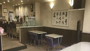 Un restaurant avec des tables et des chaises, un comptoir et un mur où sont inscrits des messages.