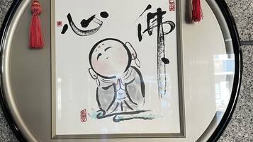 A framed artwork with calligraphy and a red tassel, hanging on a wall.