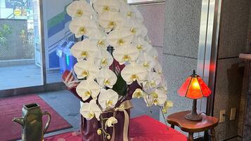 A table with a vase of white orchids, a decorative pitcher, and a small table lamp.