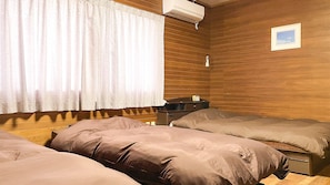 A room with two beds, wooden walls, a nightstand, and a framed picture on the wall. - Minshuku Kunya (Ishigaki)