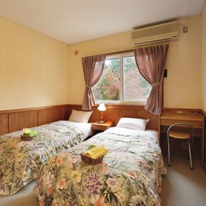 A room with two beds, a desk, and a chair. - Pension Flying Jeep (Minamiaso)