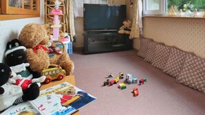 Uma sala de estar aconchegante com televisão, brinquedos de pelúcia e brinquedos infantis espalhados.