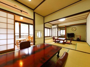 Une pièce de style japonais traditionnel, avec un sol recouvert de tatamis, une table en bois et un téléviseur.