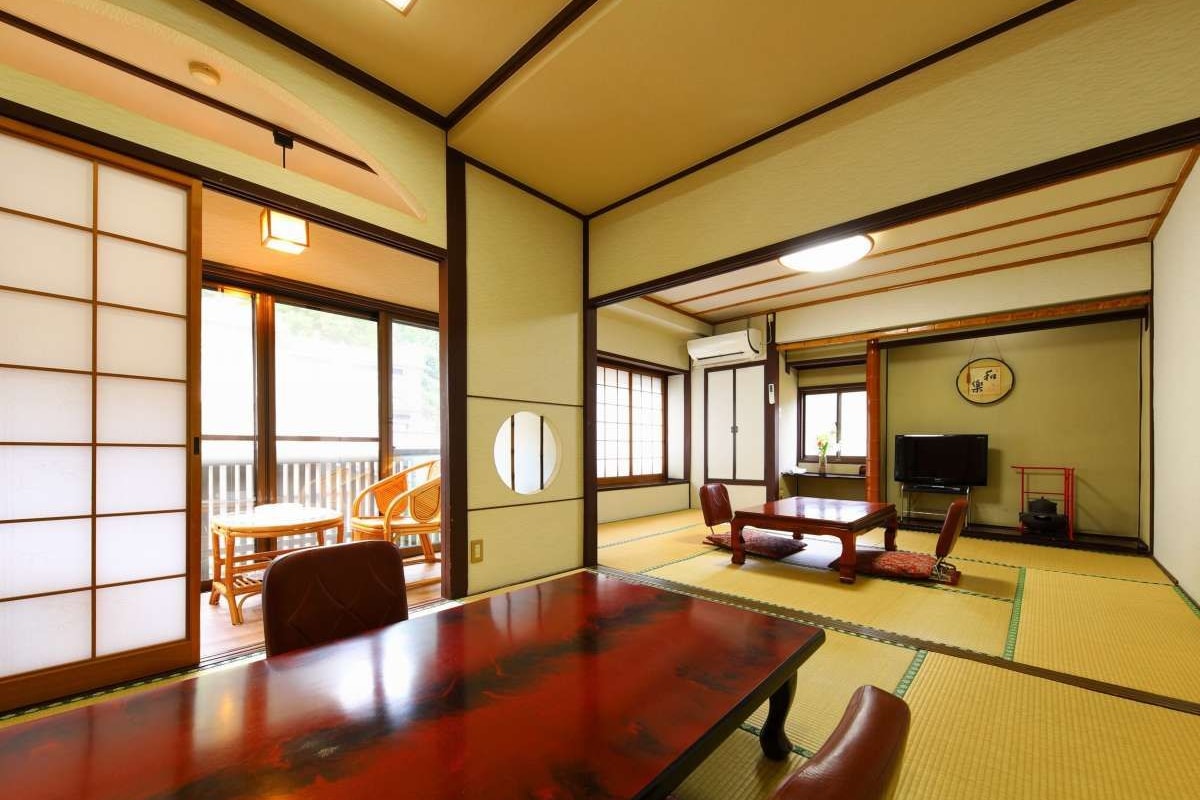 Ein traditioneller japanischer Raum mit Tatami-Bodenbelag, einem Holztisch und einem Fernseher.