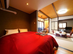 Ein Hotelzimmer mit einem großen Bett, einem Schreibtisch mit Stuhl, einem Fernseher und einem durchgegangenes Badezimmer.