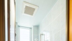 A small, modern bathroom with a shower, a toilet, and a window. - Pension Umi to Yama (Nago)