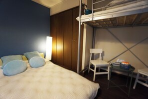 Ein Stockbett mit Schreibtisch und Stuhl, ein Nachttisch mit Lampe sowie ein kleiner Tisch mit einem Korb.