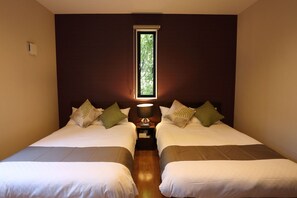 Une chambre avec deux lits, une fenêtre donnant sur un paysage verdoyant et une table de chevet avec une lampe.