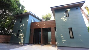 Une maison moderne à deux étages, dotée d’un toit plat, de grandes fenêtres et d’une entrée en briques.