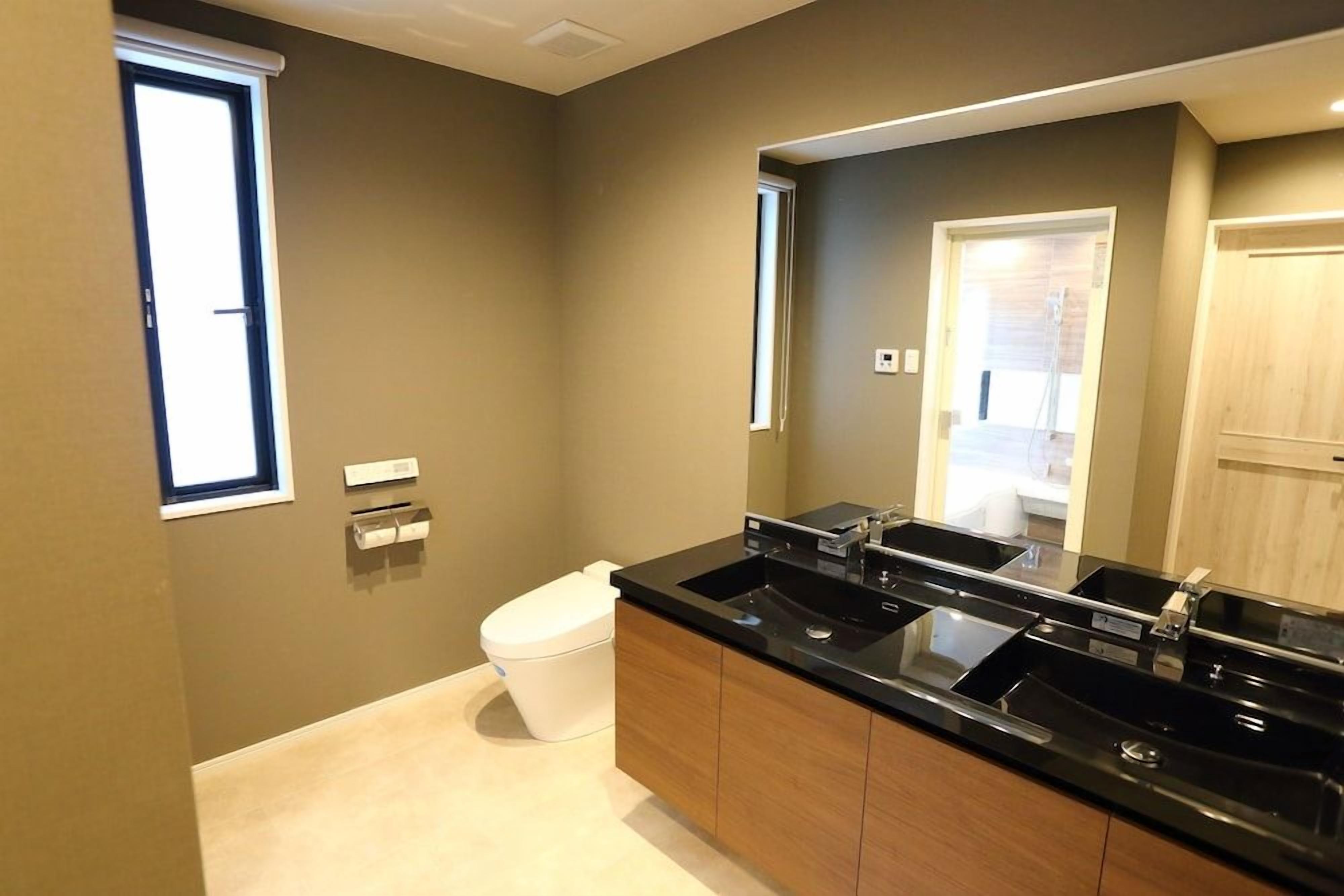 A modern bathroom with a large sink, toilet, and mirror.