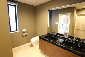 Een moderne badkamer met een groot wastafel, toilet en spiegel.