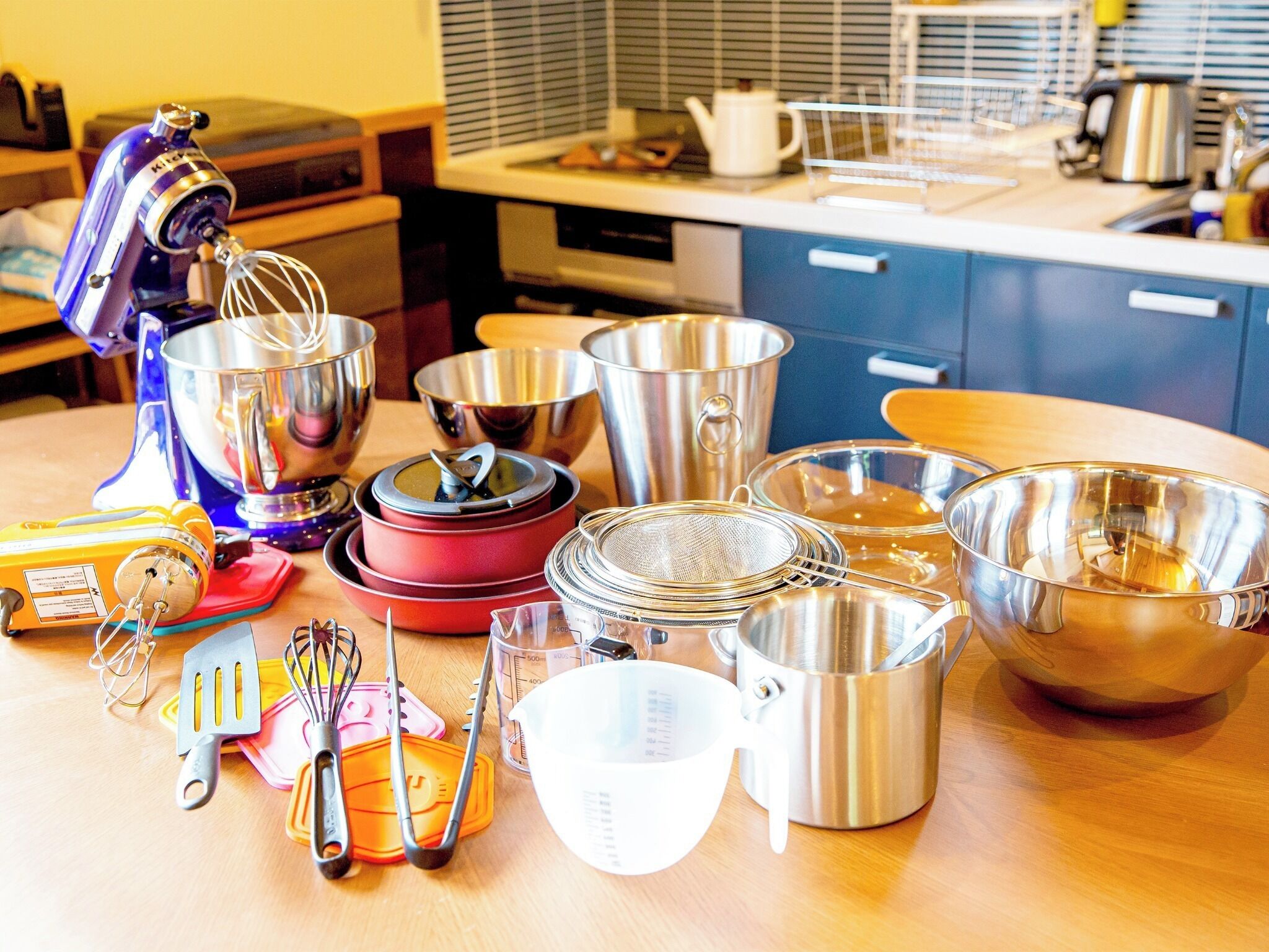 A kitchen with various utensils and cookware, including a stand mixer, pots, pans, and measuring cups.