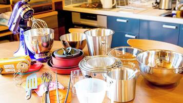A kitchen with various utensils and cookware, including a stand mixer, pots, pans, and measuring cups.