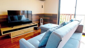 A modern living room with a flat-screen TV, a wooden entertainment unit, and a large grey sofa. - Tenkyu Inn (Nanjo)