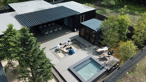 Une terrasse extérieure moderne, dotée d’un foyer, de sièges et d’une piscine.
