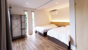 Une chambre d’hôtel avec deux lits, un plancher en bois, une armoire avec un miroir et un appareil de climatisation fixé au mur.