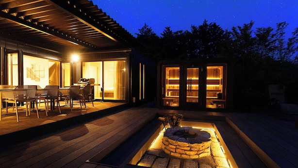 Une terrasse extérieure moderne comprenant un espace repas, un barbecue et un foyer en pierre.