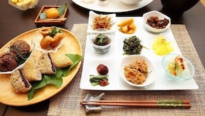 Une table où l’on trouve divers plats, notamment des plats frits, des légumes et un bol de soupe.
