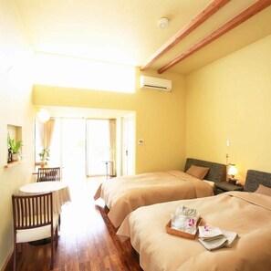 A hotel room with two beds, a small table, and a chair. There is a window with curtains, a ceiling fan, and an air conditioning unit. - Hanaribira (Uruma)