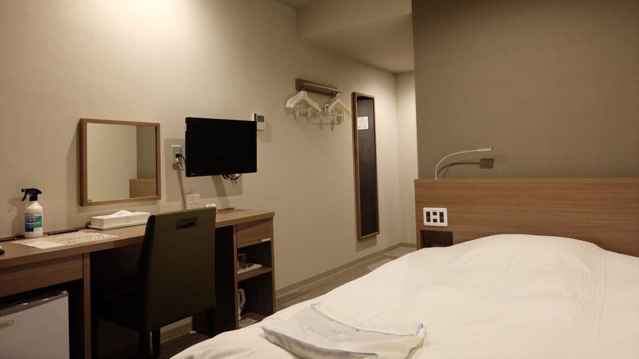 Une chambre d’hôtel équipée d’un lit, d’un bureau, d’une chaise et d’un téléviseur.