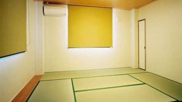 A room with tatami mats, a wooden ceiling, and a yellow wall. - Hotel Ikoi (Tenri)