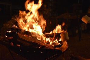 Ein Lagerfeuer mit Holzscheiten und einem Marshmallow auf einem Grill.