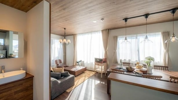 Ein modernes Wohnzimmer mit Holzboden, einem Essbereich mit großem Tisch und einer Küchenzeile mit Spüle und Schränken.