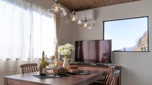 Ein Essbereich mit Holztisch, Stühlen, einer Weinflasche und einem Blumenstrauß.
