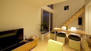 A modern living room with a flat-screen TV, a wooden coffee table, and a dining area with a long table and chairs. - Co-ya-do Nasu (Nasu)