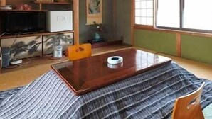 Una habitación tradicional japonesa con suelo de tatami, una mesa baja, un televisor y una ventana con vistas.