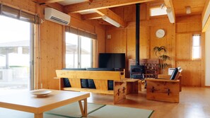 A wooden interior with a sofa, a television, a fireplace, and a dining table.