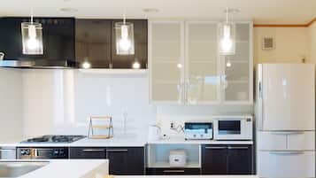 A modern kitchen with dark wood cabinets, white countertops, and stainless steel appliances including a stove, microwave, and refrigerator.