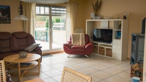 Ein Wohnzimmer mit Sofa, Sessel, TV-Schrank und Essbereich.