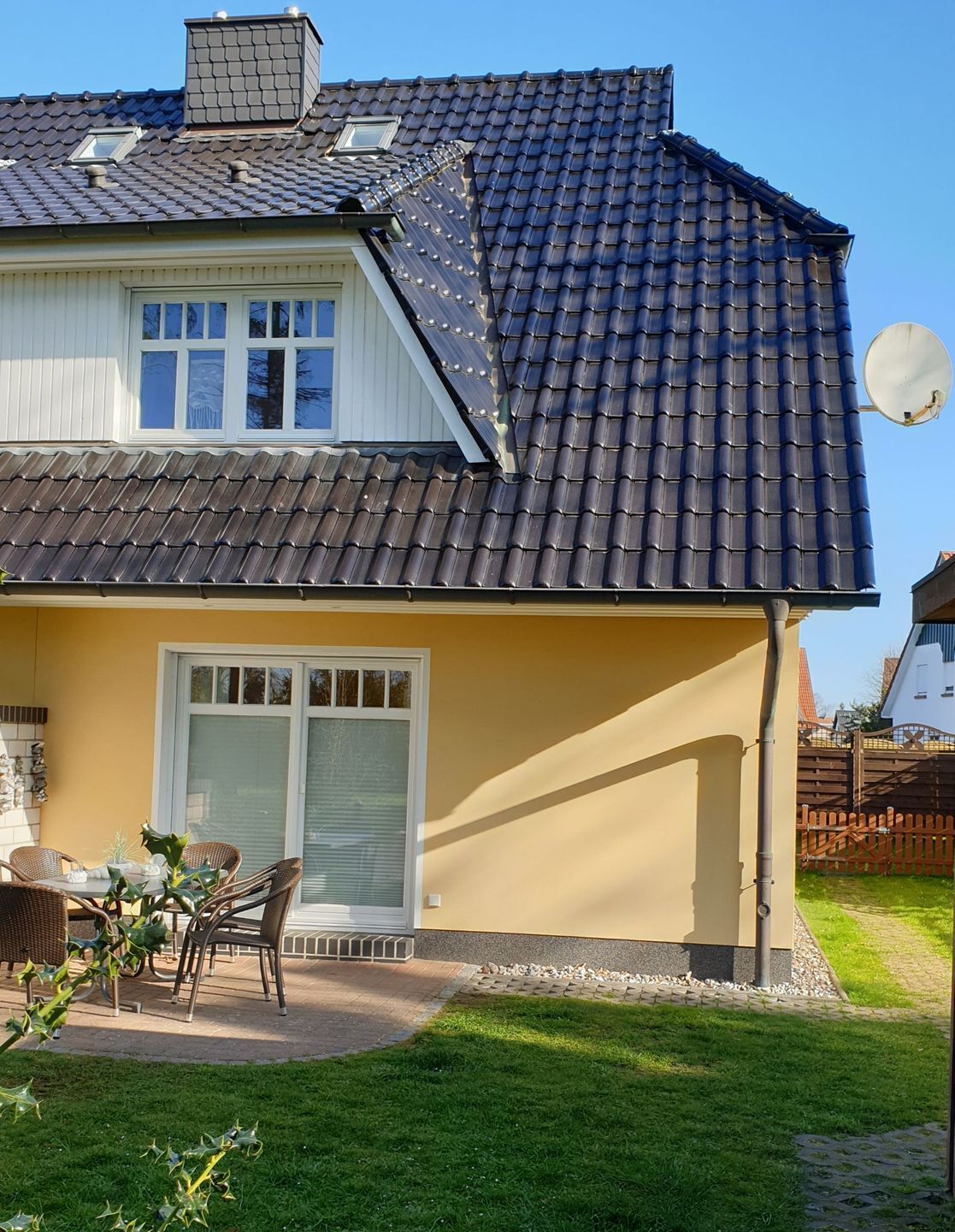 A house with a tiled roof, a satellite dish, and a patio with outdoor furniture.