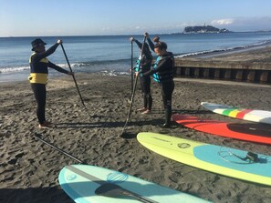 Une plage où l’on peut faire du paddle, avec des personnes debout sur leurs planches, tenant une pagaie.