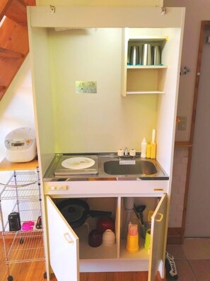 Une petite cuisine équipée comprenant un évier, une cuisinière et des étagères de rangement.