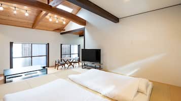 Ein modernes Schlafzimmer mit einem großen Bett, einem Fernseher und einem Essbereich mit Stühlen.