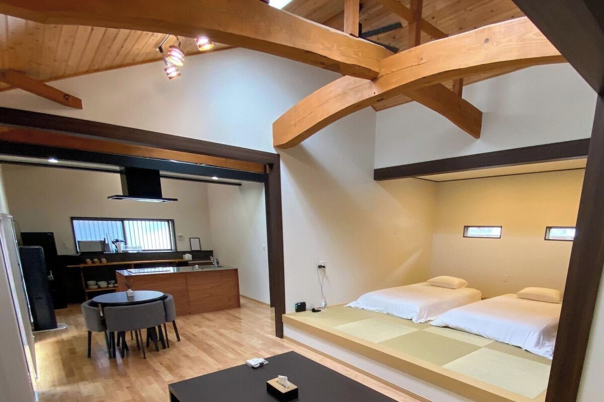 A compact hotel room with a kitchenette, a dining area, and two beds.