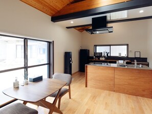 Una cocina moderna con una isla central, un comedor con mesa y sillas, y amplios ventanales que brindan luz natural.