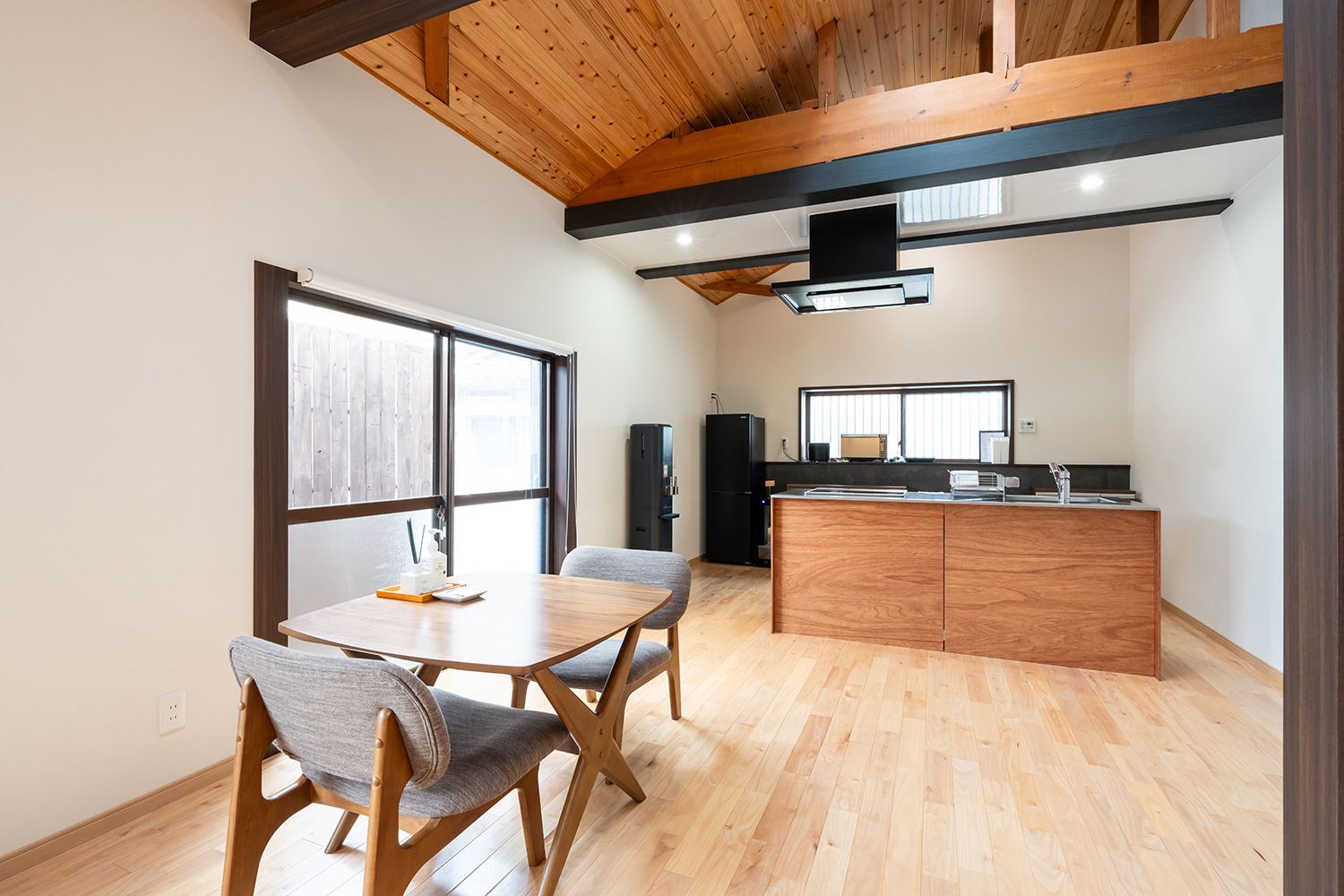 A modern kitchen with a wooden island, a dining area with a table and chairs, and a large window providing natural light.
