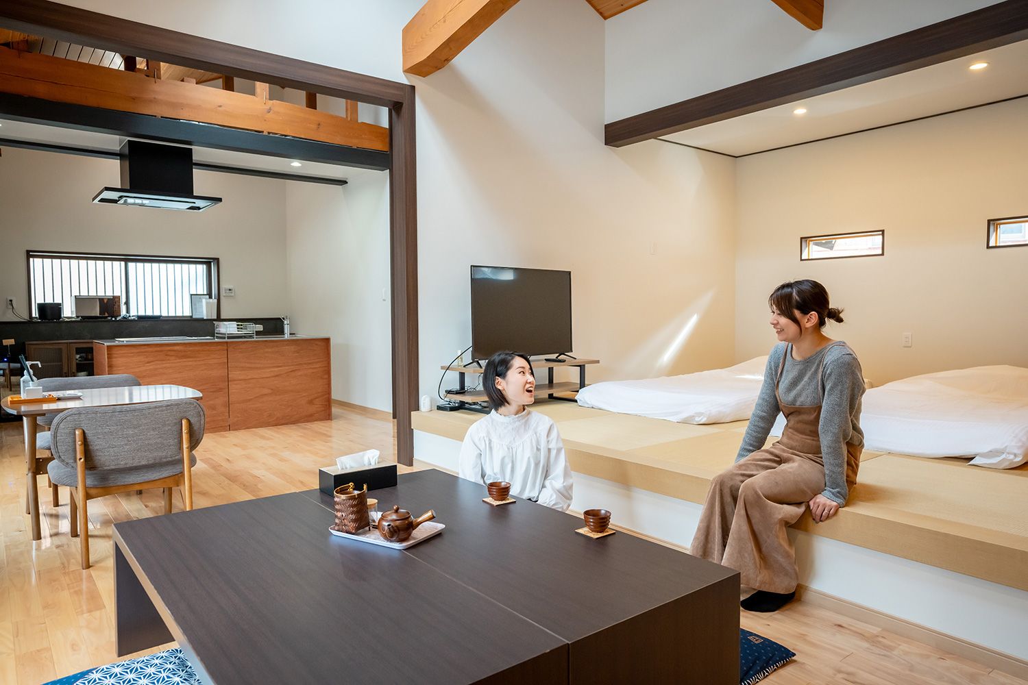 A modern hotel room with a dining area, a TV, and a bed.
