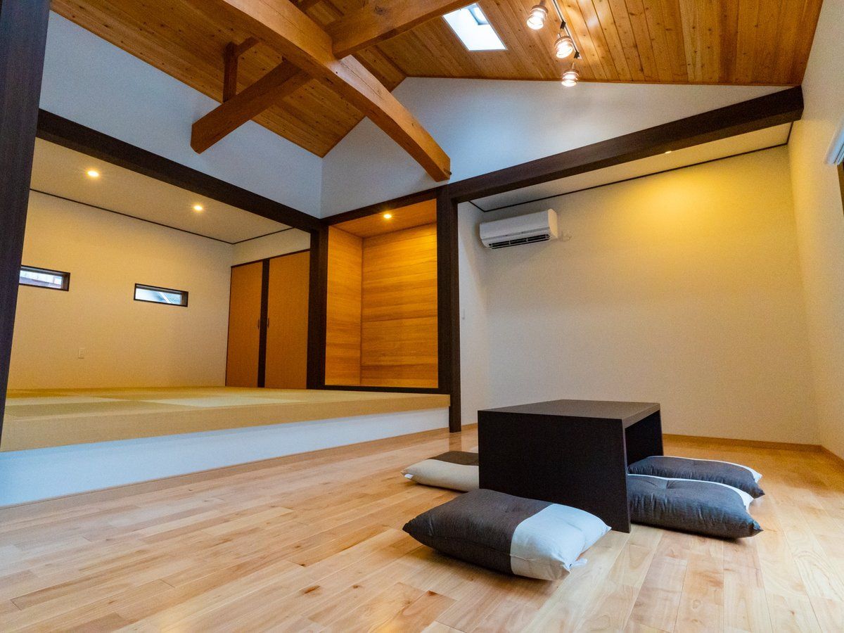 Ein Zimmer mit Holzboden, einem schwarzen Tisch und Kissen.