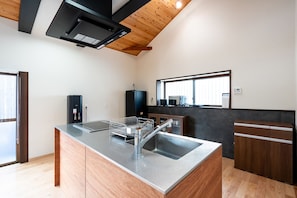 A modern kitchen with a central island, wooden ceiling, and built-in appliances. - Miyako Bettei (Goto)