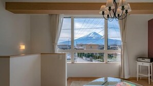 A room with a glass table, a view of a mountain, and a white cabinet. - Villa Fuji Bon Voyage Sora (Fujikawaguchiko)