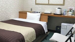 Ett hotellrum med två sängar, ett skrivbord med en dator, en stol, en papperskorg och en minibar.