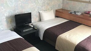 Ett hotellrum med två sängar, en TV, ett sängbord och ett litet bord vid sängen.